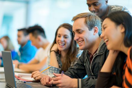 Quatre étudiants souriants devant un ordinateur